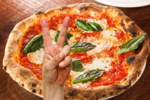 pizza e mano che indicano un due