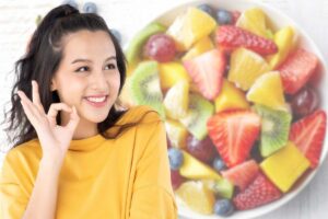 Ragazza fa segno "ok" e frutta