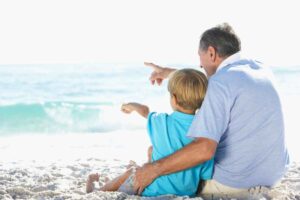 Nonno e nipote seduti in spiaggia ad ammirare il mare