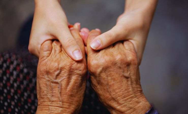 mani di una giovane con quelle di un'anziana