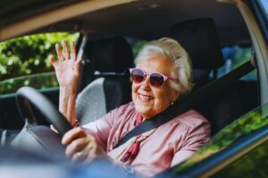 anziana al volante saluta