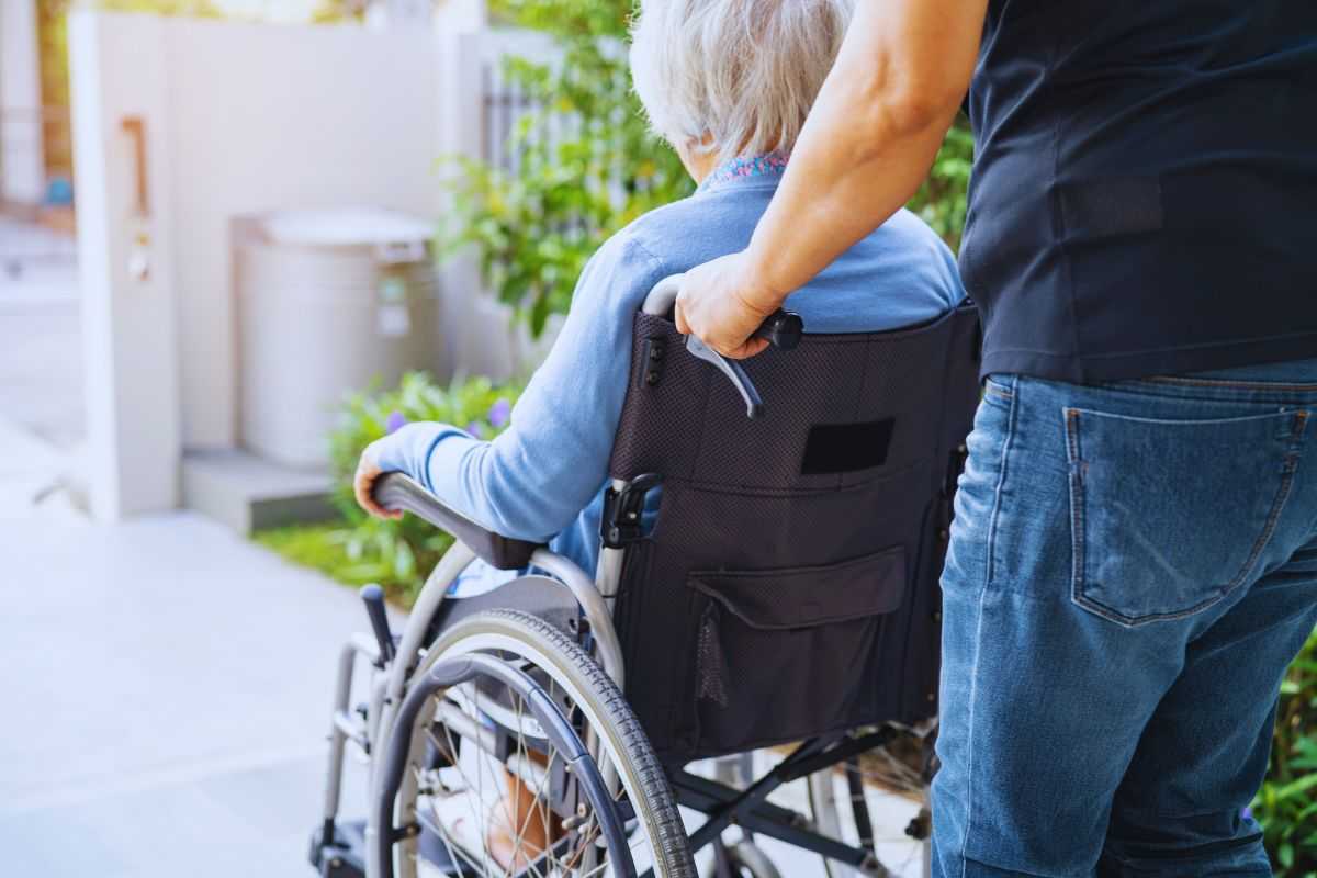 una signora anziana portata in sedia a rotelle