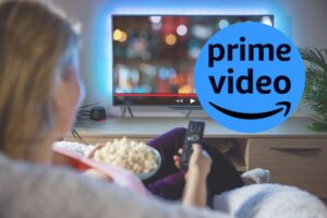 una persona guarda la tv con i popcorn e nel cerchietto il logo di prime